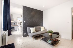A modern living room with a grey sofa, a coffee table, and a dark brick accent wall. - Villa Mont Plaisir, just a stone's throw from the beach. Pets allowed. (Langrune-sur-Mer)