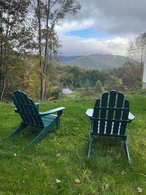 Two Adirondack chairs facing a scenic view of a valley with trees and a house in the background. - The Carriage Barn: new build with expansive mountain views and walk to Dorset (Dorset)