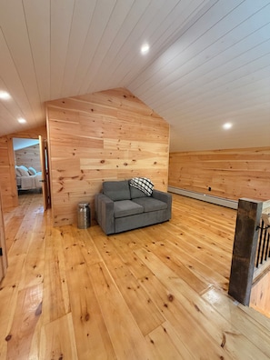 A room with a wooden ceiling, a grey sofa, and a wooden floor. - The Carriage Barn: new build with expansive mountain views and walk to Dorset (Dorset)