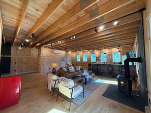 A spacious living area with a wooden ceiling, a red appliance, a sofa, a coffee table, and a fireplace. - The Carriage Barn: new build with expansive mountain views and walk to Dorset (Dorset)