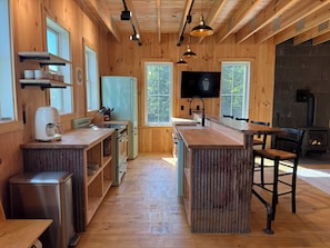 A wooden interior with a kitchen, bar area, and seating. - The Carriage Barn: new build with expansive mountain views and walk to Dorset (Dorset)