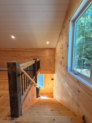 A wooden interior with a staircase leading to a lower level, a window with a view of trees, and a ceiling with recessed lighting. - The Carriage Barn: new build with expansive mountain views and walk to Dorset (Dorset)