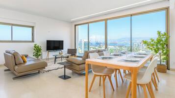 Una sala moderna con un sofá, un televisor y una zona de comedor con una mesa dispuesta para cuatro.