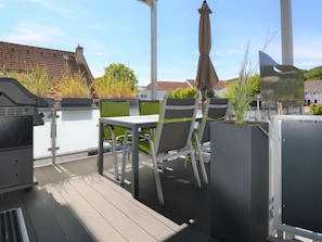 An outdoor patio with a table and chairs, a barbecue grill, and potted plants. - Holiday Apartment With 3 Bedrooms (Sassnitz)