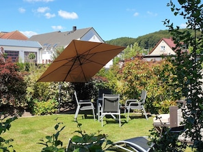 A patio with a table and chairs, a large umbrella, and a view of houses in the background. - Holiday Apartment With 3 Bedrooms (Sassnitz)