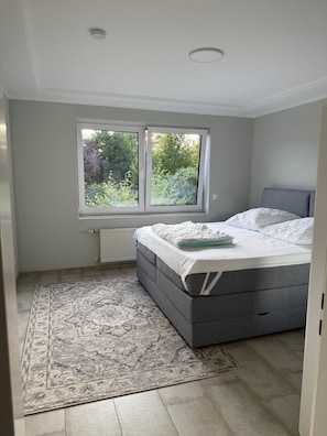Ein Schlafzimmer mit einem Bett, einem Fenster, einer Heizung und einem gemusterten Teppich.