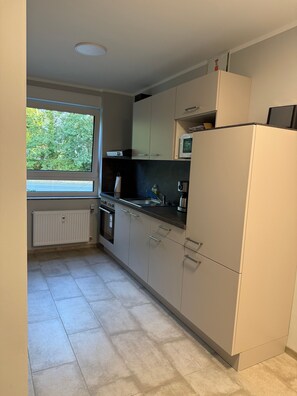 Eine moderne Küche mit Fenster, eingebauten Geräten und Fliesenboden.