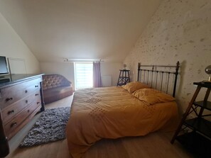 Ein Schlafzimmer mit einem Bett, einem Schminktisch, einem Fenster mit Vorhängen und einer Heizung.