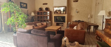 A cozy living room with a fireplace, leather sofas, a rocking horse, and a wooden coffee table.