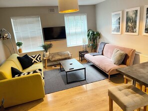 A modern living room with a yellow sofa, a pink sofa, a coffee table, and a TV. - Bright Home Near Central London - Near Emirates Stadium (London)