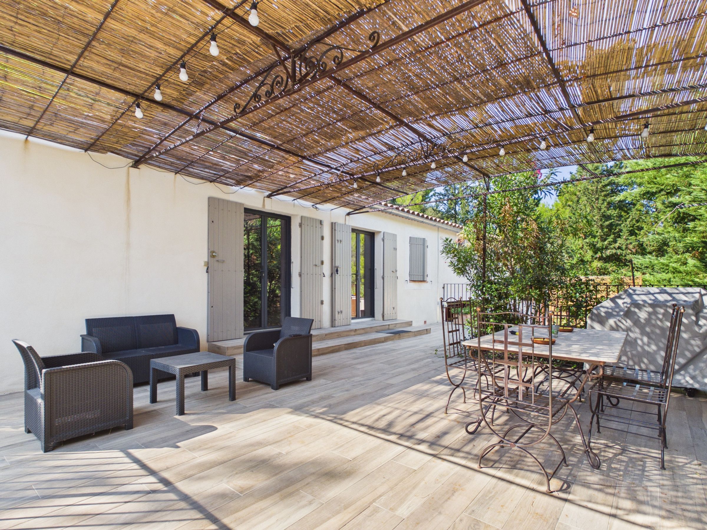 Une terrasse extérieure aménagée avec des meubles en osier, une table et des chaises.