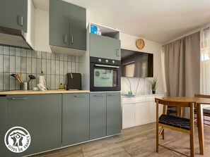 Eine moderne Küche mit grauen Schränken, einem eingebauten Ofen und einem Essbereich mit Holztisch und Stühlen.