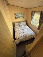 Un dormitorio con una cama, un cuadro en la pared y una ventana con cortinas.