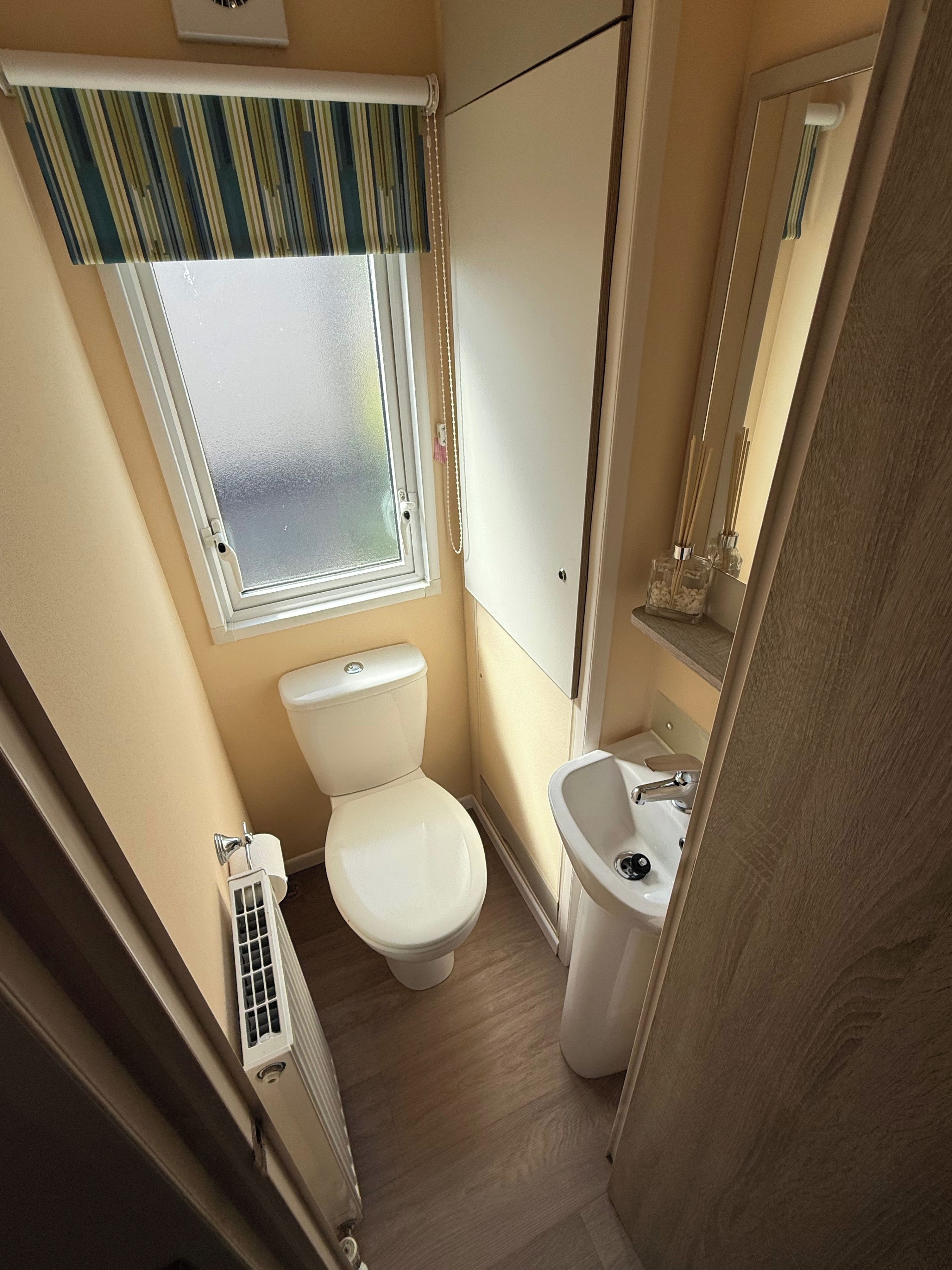 A compact bathroom with a toilet, sink, and window.