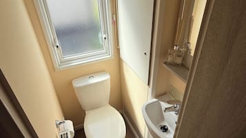 A compact bathroom with a toilet, sink, and window.