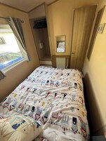 Un dormitorio con cama, ventana, armario y espejo.