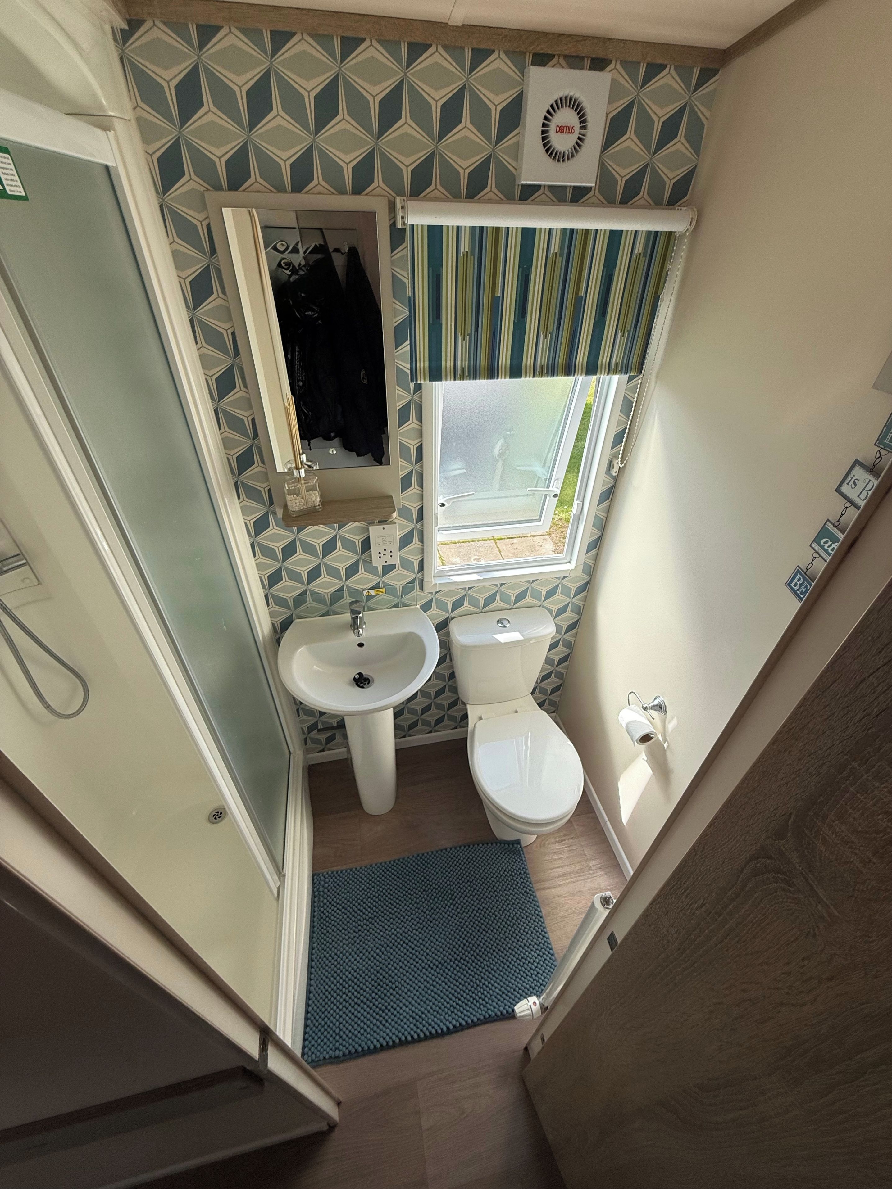 A compact bathroom with a toilet, sink, and shower.