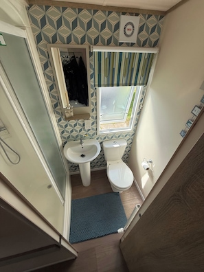 A compact bathroom with a toilet, sink, and shower. - Static Caravan Sleeps 6 Close to Amenities (Clacton-on-Sea)