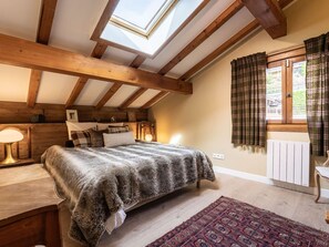 A bedroom with a skylight, wooden beams, a bed with a blanket, a bedside table with a lamp, a radiator, and a window with curtains. - Spacious chalet in Bozel - 10 guests (Bozel)