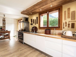 A modern kitchen with white cabinets, a wooden ceiling, and a large window with a view of greenery. - Spacious chalet in Bozel - 10 guests (Bozel)