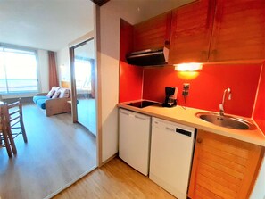 A compact kitchen with a dishwasher, a coffee maker, and a sink. There is a dining area with a chair and a sofa. - Studio cabin valley view - 6 guests (Piau-Engaly)