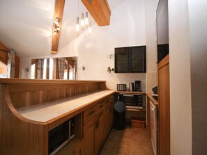 Ett kompakt kök med träinredning, en inbyggd ugn, en kaffebryggare och en mikrovågsugn.