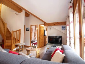 A cozy living room with a staircase, a sofa, a coffee table, and a television. - Duplex near slopes - 8 guests (Valloire)