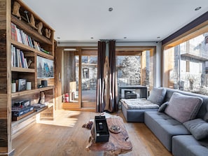 Ein modernes Wohnzimmer mit einem großen grauen Sofa, Holzregalen und einem Couchtisch aus Holz.