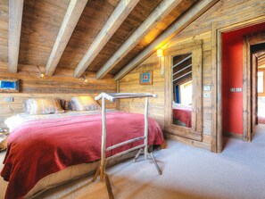 Ein Zimmer mit Holzboden, einem Bett mit roter Decke, einer Holzleiter und einer roten Tür.