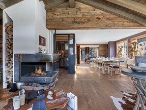 Ein großzügiger Wohnbereich mit Kamin, Holzboden und einem Essbereich mit Tisch und Stühlen.
