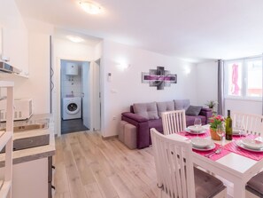 A modern apartment with a dining area, a sofa, a washing machine, and a kitchen. - Denise With a Pleasant Terrace (Liznjan)