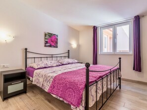 A bedroom with a bed, bedside table, and a window with curtains. - Denise With a Pleasant Terrace (Liznjan)