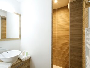 Ein modernes Badezimmer mit einem großen Spiegel, einem weißen Waschbecken und Holzvertäfelung an den Wänden.