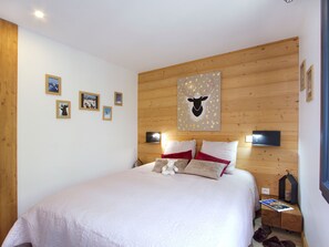 Ein Schlafzimmer mit einem großen Bett, einem Holzkopfteil, Wandleuchten und gerahmten Bildern.