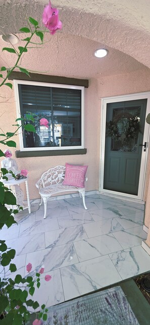 A patio area with a bench, a door, and a window with blinds. - Deluxe 4-bedroom home with AC in pleasant Las Vegas l. A perfect retreat for you (Las Vegas)
