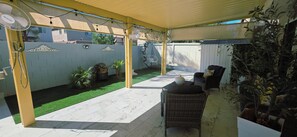 An outdoor patio area with a covered seating area, a small garden, and a white fence. - Deluxe 4-bedroom home with AC in pleasant Las Vegas l. A perfect retreat for you (Las Vegas)
