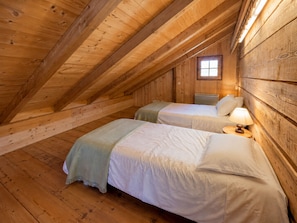 A cozy attic bedroom with two beds, wooden beams, a window, and a nightstand with a lamp. - Savoyard mazot, pets allowed - 6 guests (Notre-Dame-de-Bellecombe)