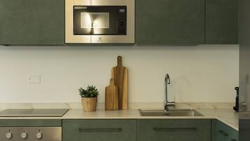 Une cuisine équipée d’un four à micro-ondes encastré, d’un évier et d’une cuisinière.