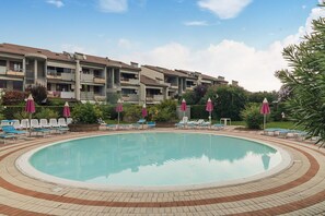 A swimming pool with lounge chairs and umbrellas, surrounded by a brick walkway. - Apartment 'Gioiello' with Shared Pool, Wi-Fi and Air Conditioning (Desenzano del Garda)