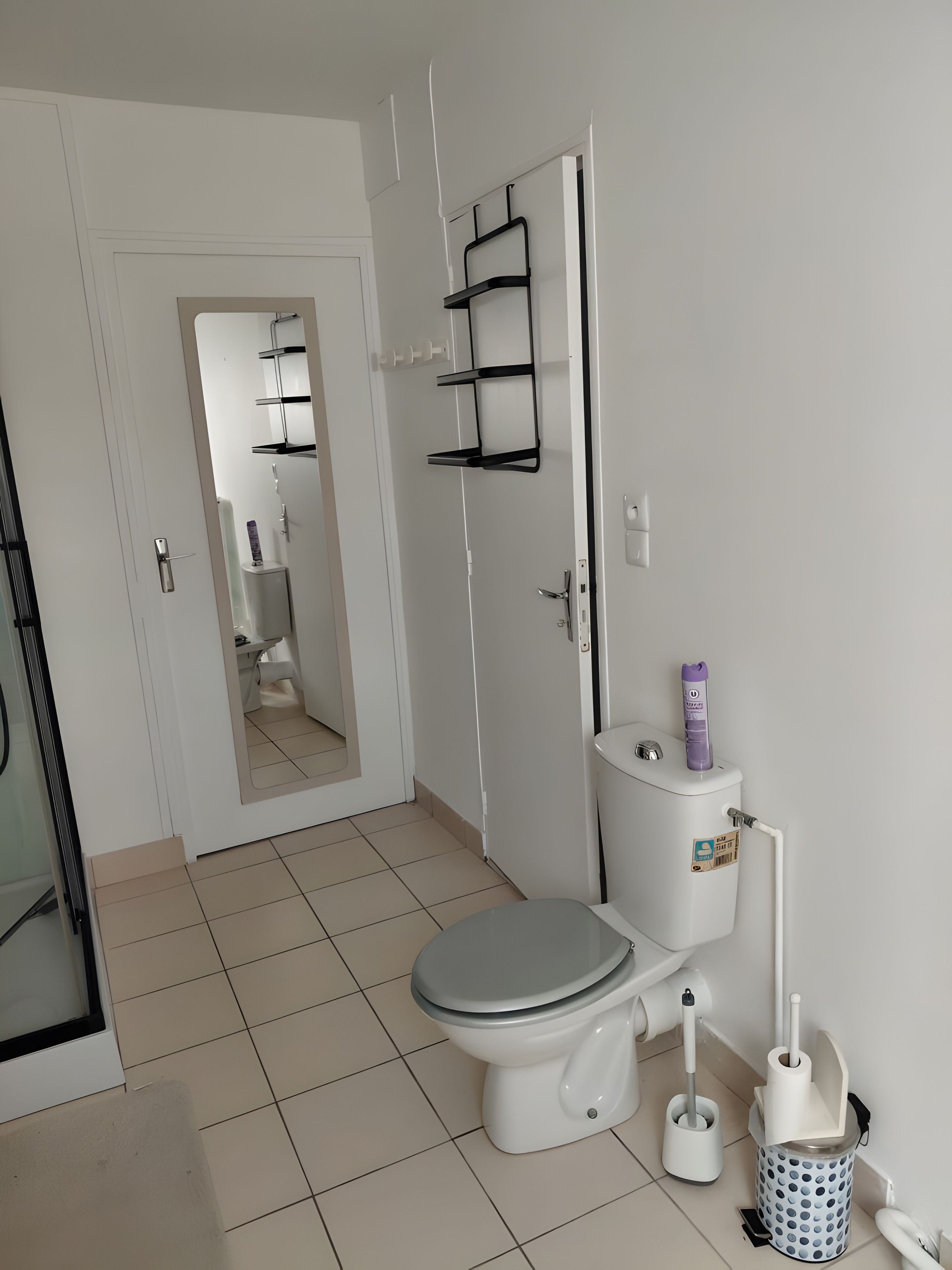 Een moderne badkamer met toilet, bidet, toiletrolhouder en een toiletborstel.