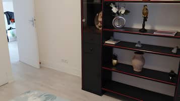 A room with a black bookshelf, a floral patterned rug, and a white door leading to another room.