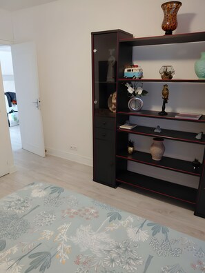 A room with a black bookshelf, a floral patterned rug, and a white door leading to another room.