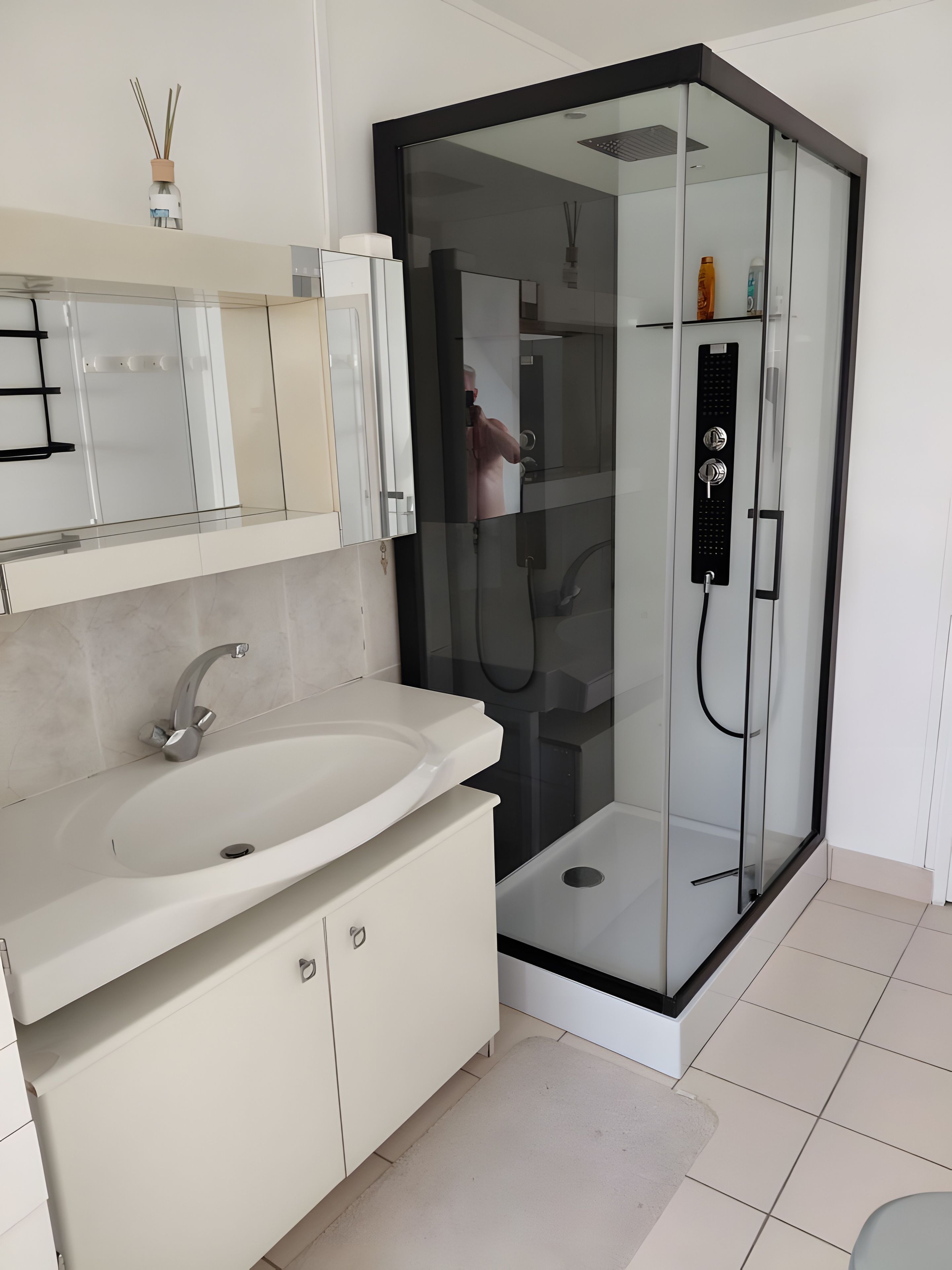 Ein modernes Badezimmer mit einer ein Glasfachwerk-Duschkabine, einem weißen Waschbecken und einem Spiegel darüber.