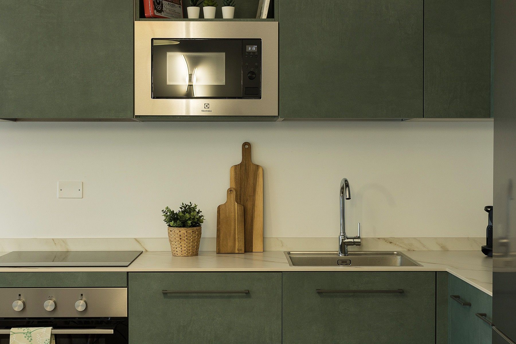 Una cucina con forno a microonde integrato, lavello e piano cottura.