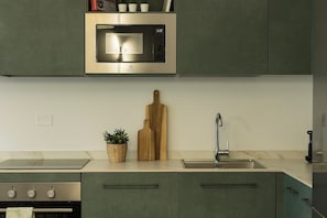 Una cucina con forno a microonde integrato, lavello e piano cottura.