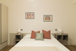 Habitación de hotel con una cama, dos mesitas de noche, dos lámparas y dos cuadros en la pared.