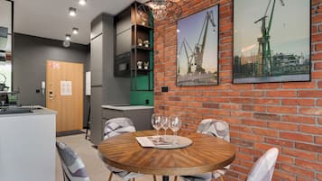 A modern kitchen with a built-in oven, a dining area with a round wooden table, and brick walls.