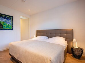 Ein Hotelzimmer mit einem großen Bett, einer Nachttischlampe und einem Gemälde an der Wand.