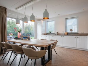 Eine moderne Küche mit weißen Schränken, einem Holztisch und Pendelleuchten.