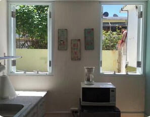 A kitchen with a microwave, a coffee maker, and a window with a view of the outside. - Perfect 1-bedroom studio with AC in soothing San Juan (San Juan)
